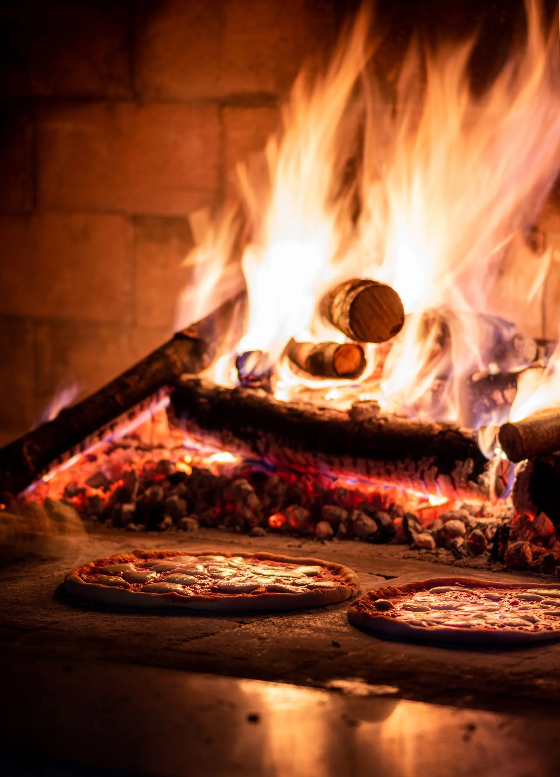 Pizzas baking in the wood-fired oven at Hearth, lit by the fire