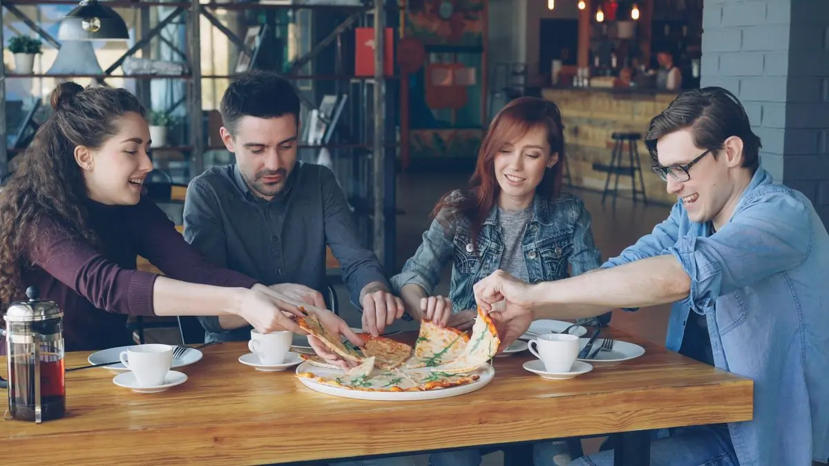 Friends sharing a pizza across a café table