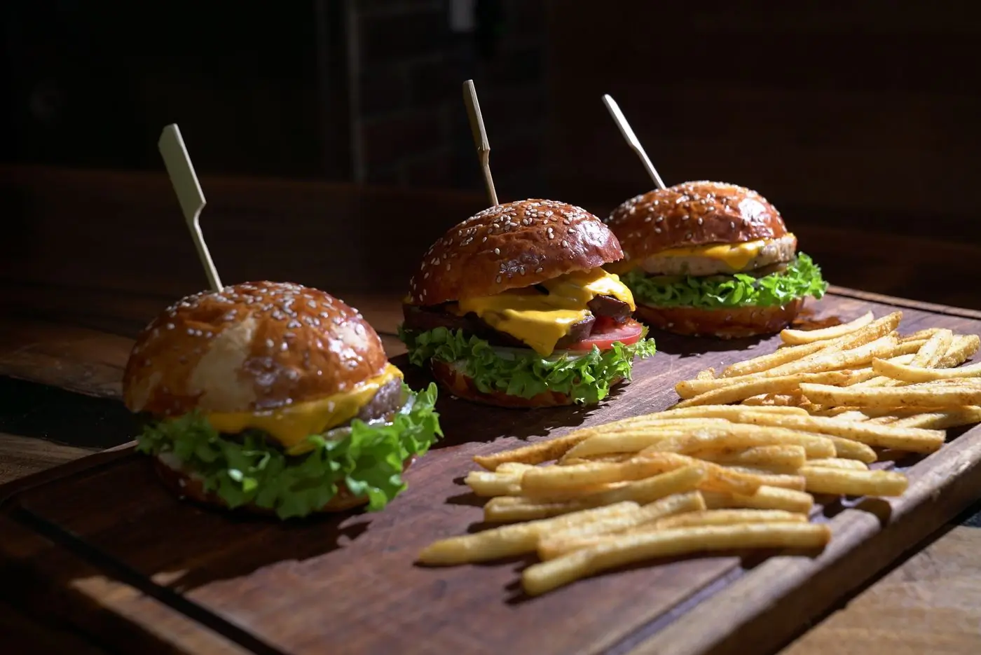 Burgers and hand-cut fries laid across a wooden platter
