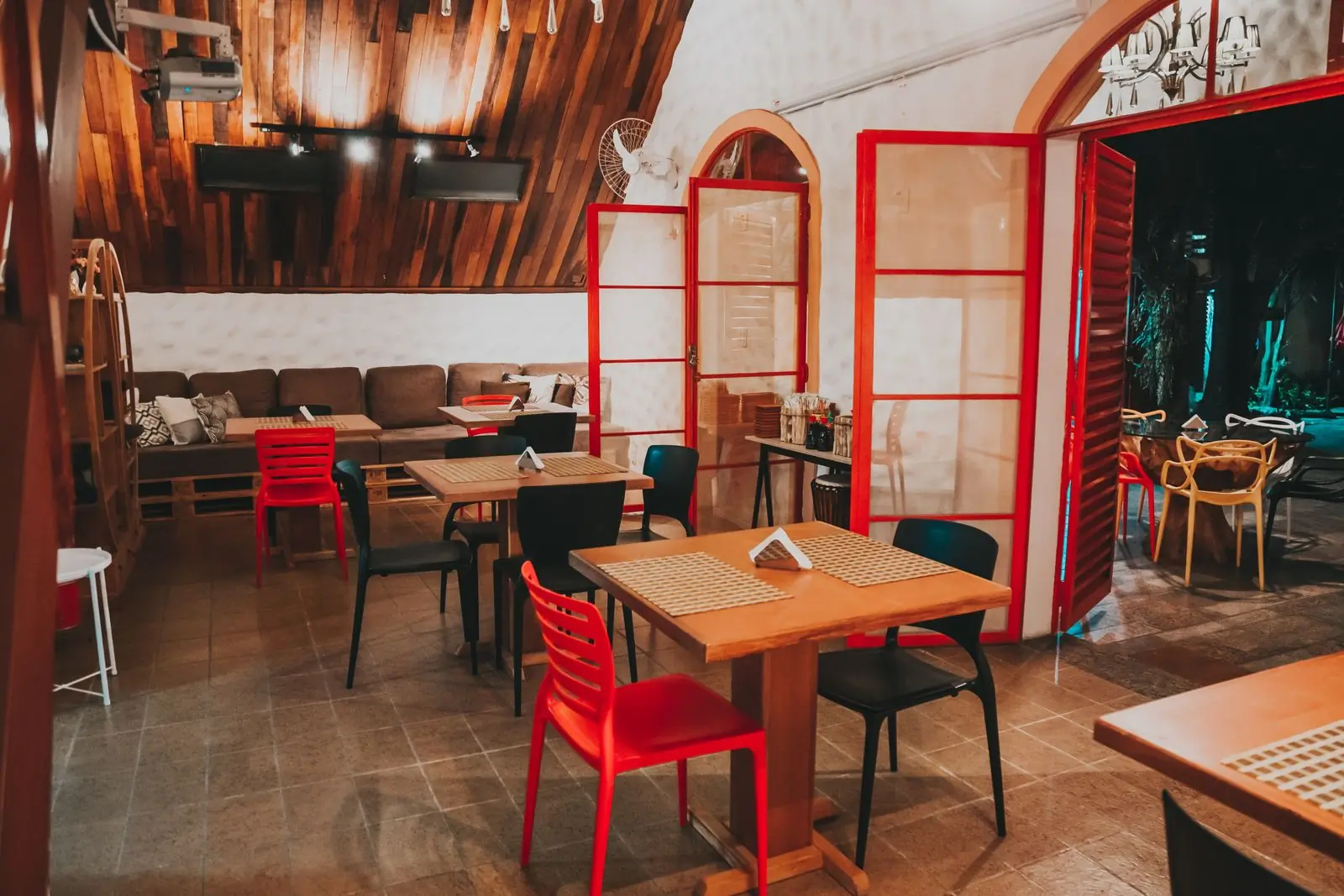The dining room at Hearth, wooden tables under red-shaded lamps