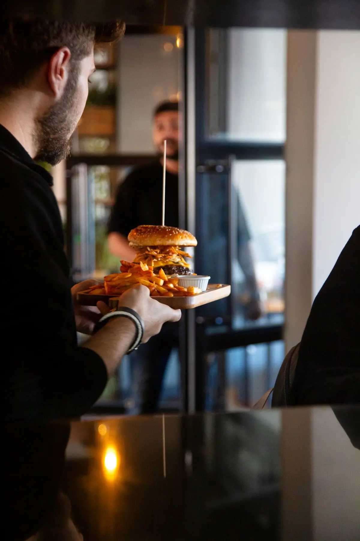 A server carrying a burger and fries through the dining room