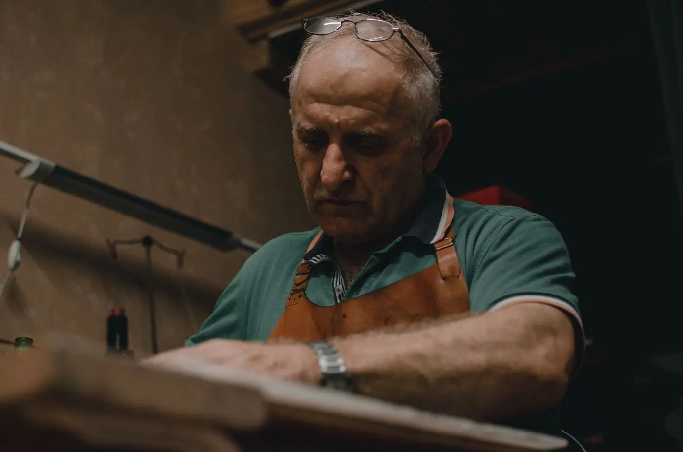 A maker working at a lit bench with hand tools
