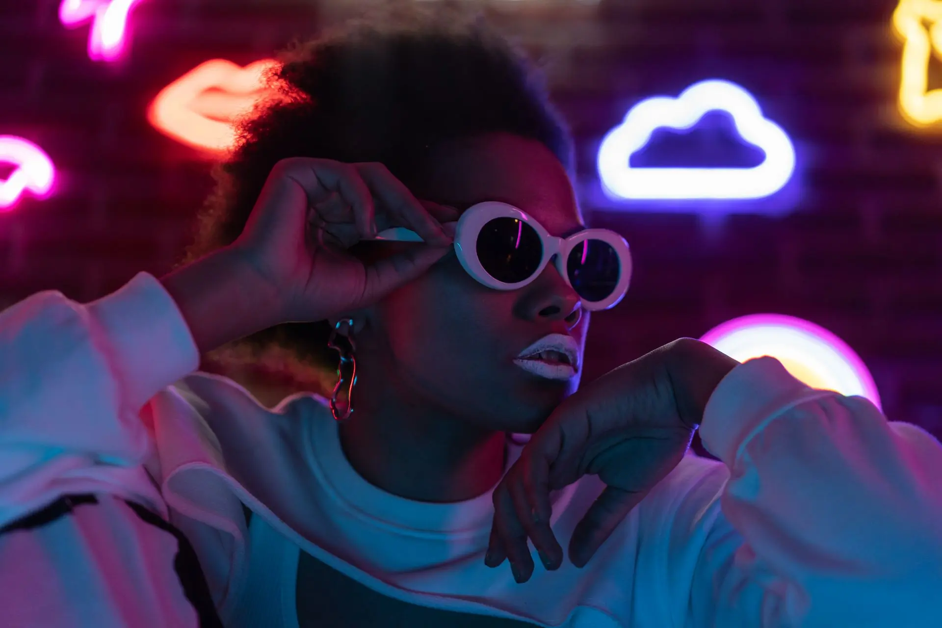 A person in white sunglasses under coloured light