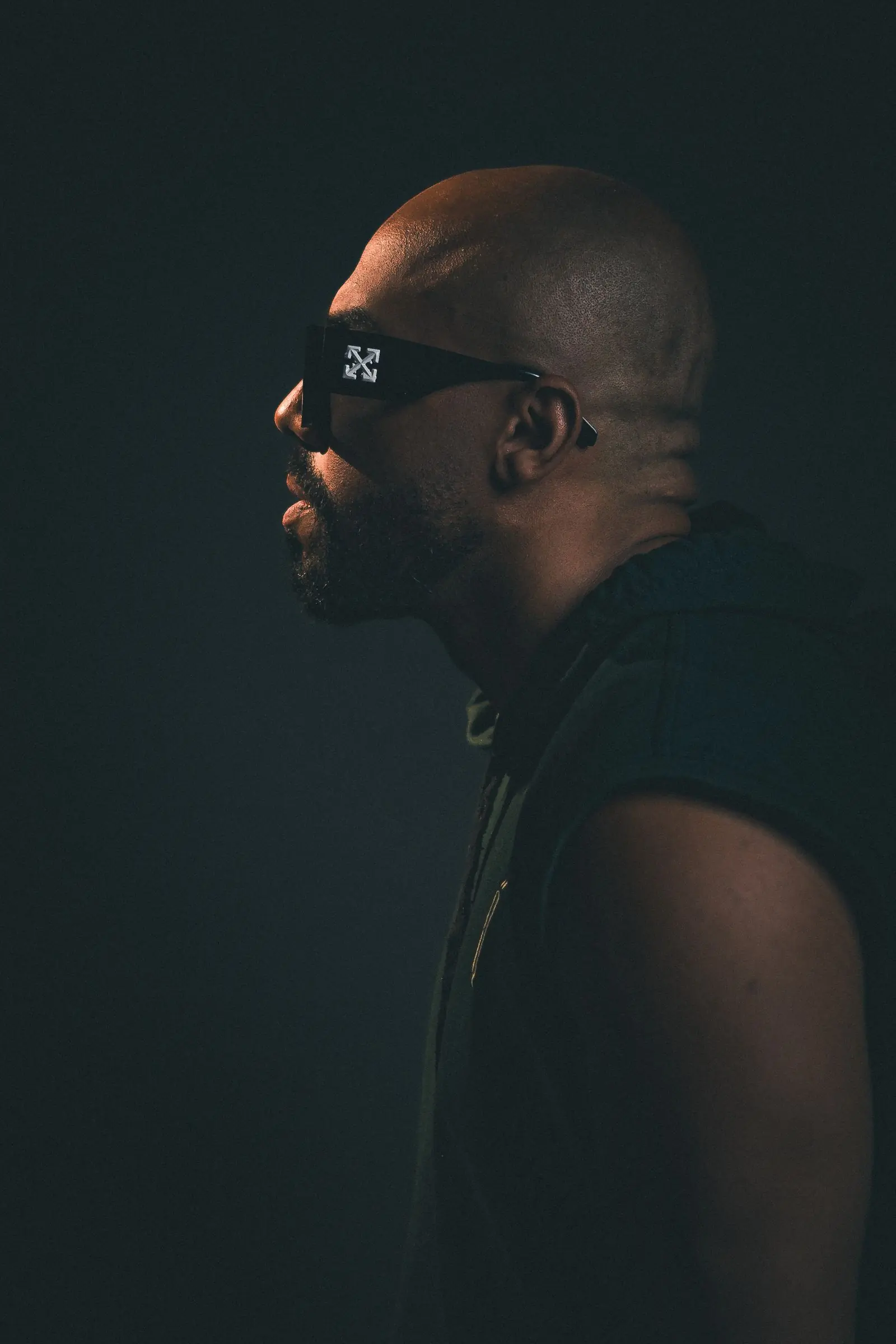 A portrait in a dark studio of a man wearing sunglasses