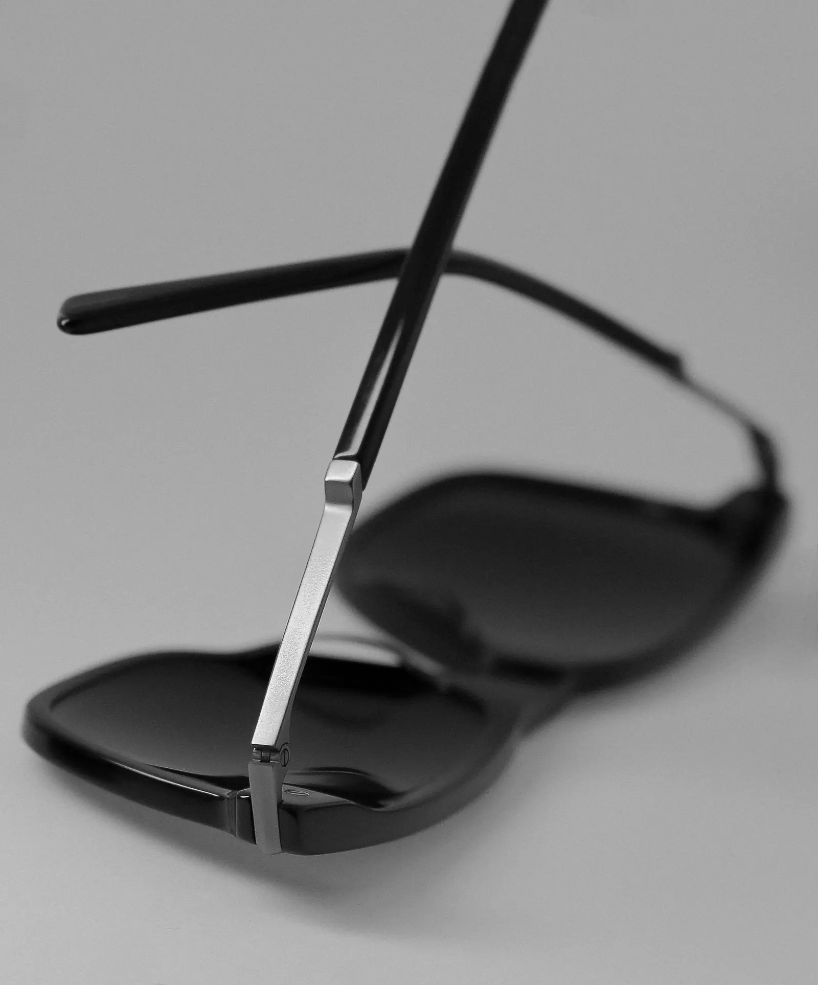 A close view of a black sunglass frame against a grey ground