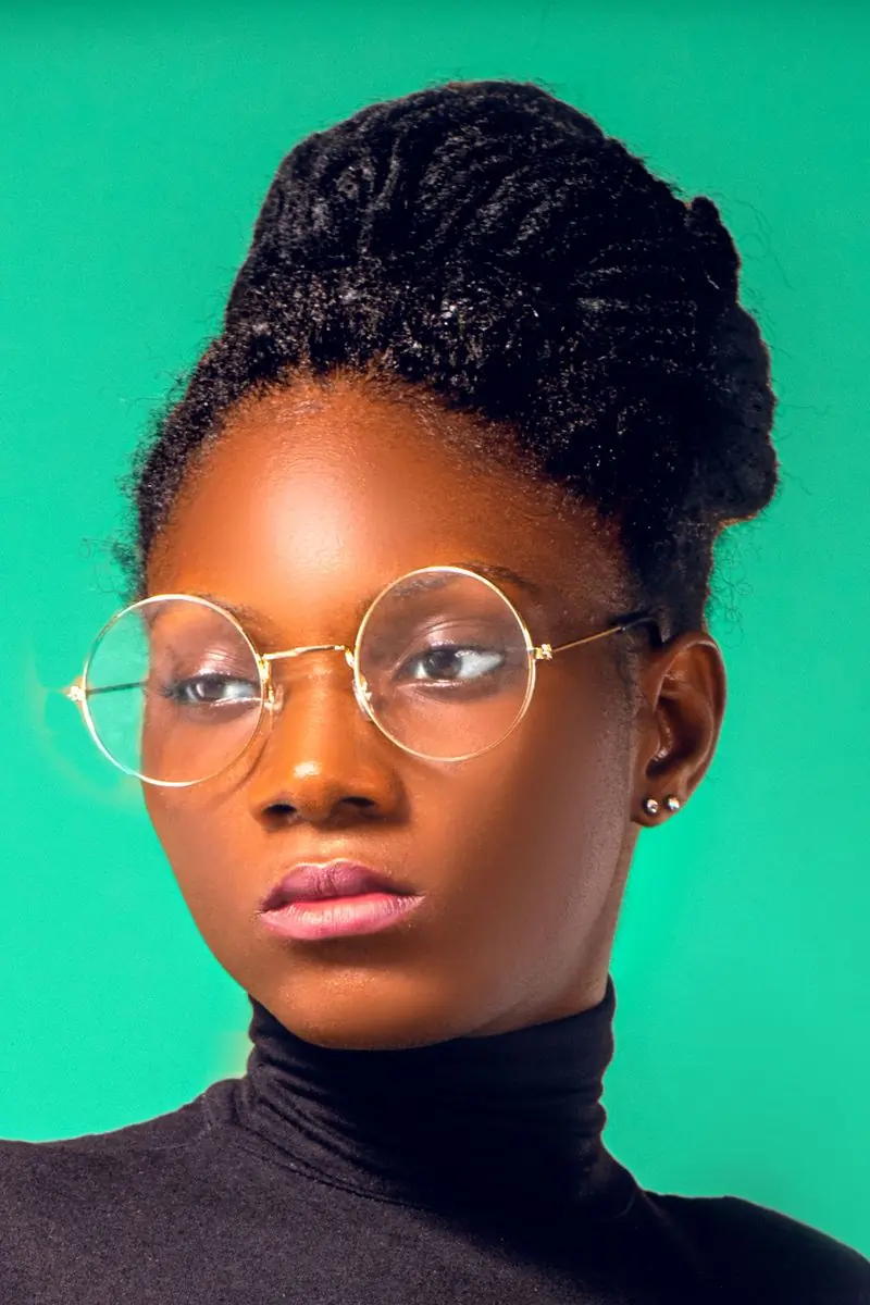 A woman in round gold frames against a green ground