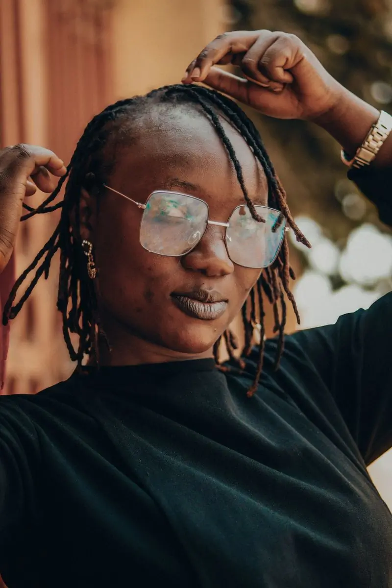 A woman with locs wearing large clear-framed glasses