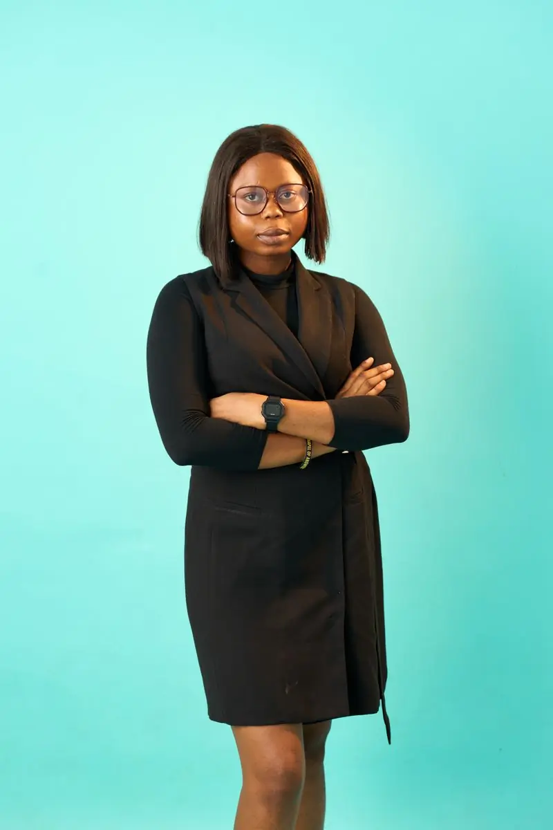 A woman in a dark jacket standing with her arms folded