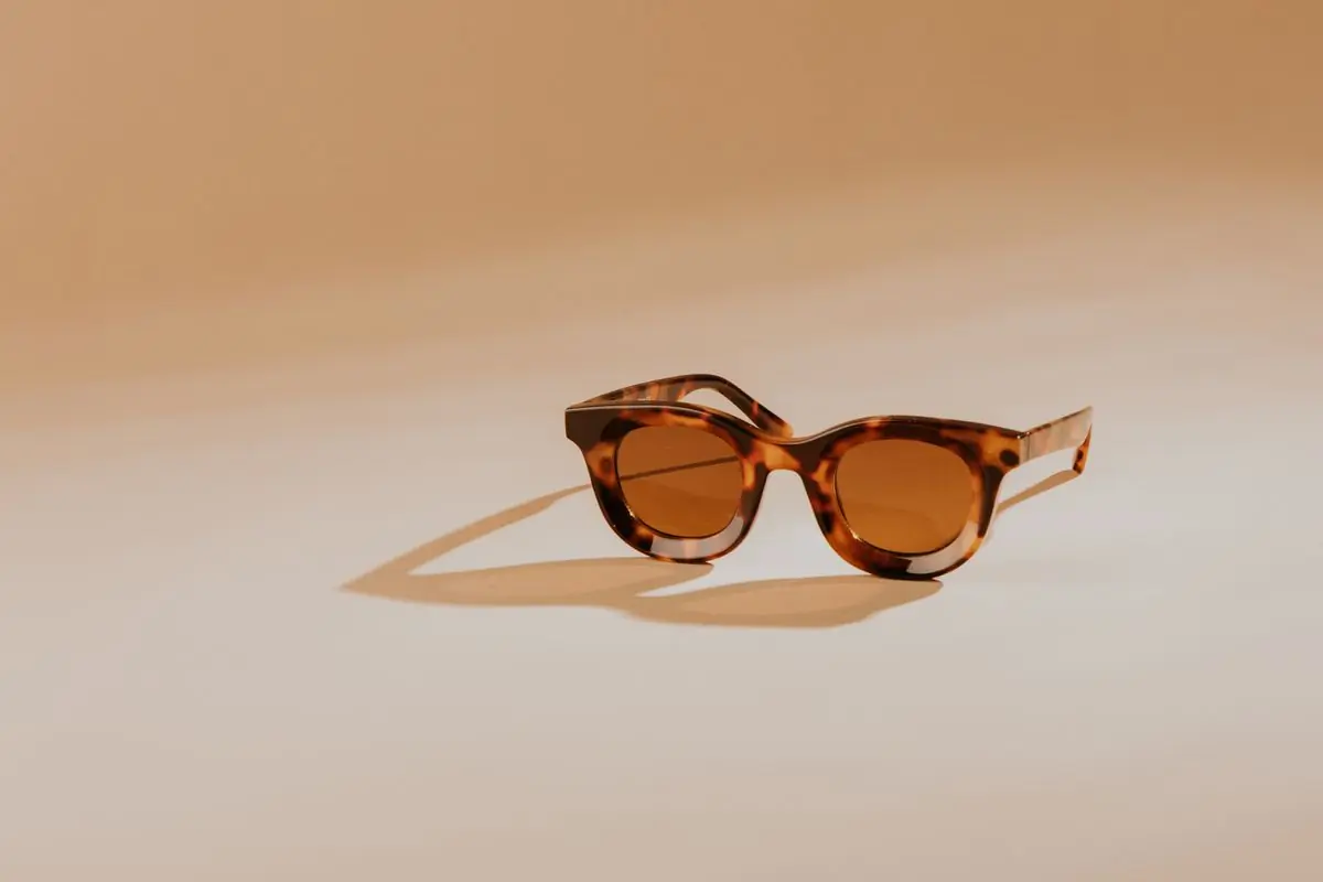 Round tortoiseshell sunglasses on a warm beige ground