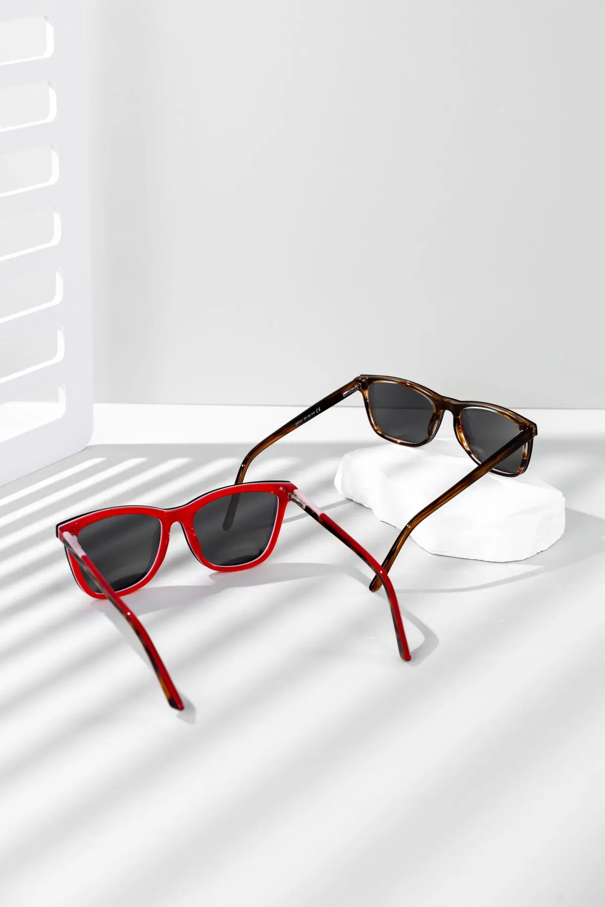 A red frame and a tortoiseshell frame casting shadows on a white ground