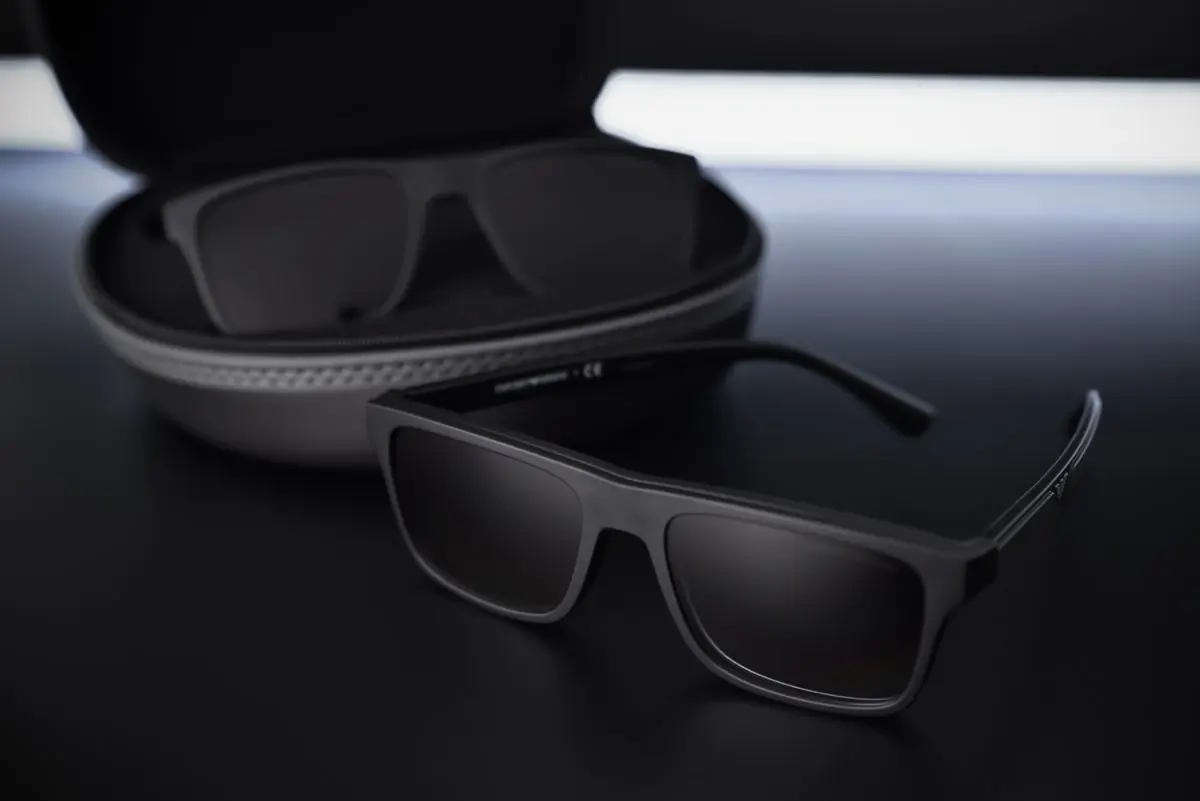 A hardshell eyewear case open beside a folded pair of sunglasses