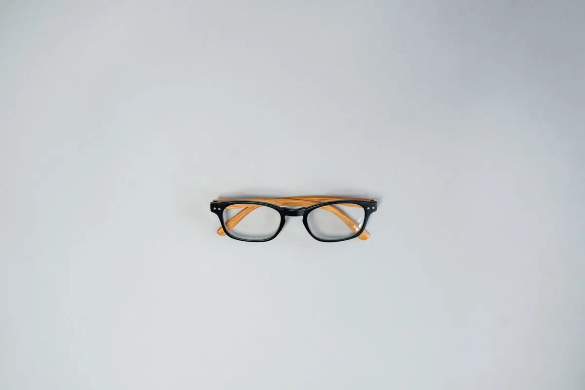 Small dark optical frames centred on a pale grey ground