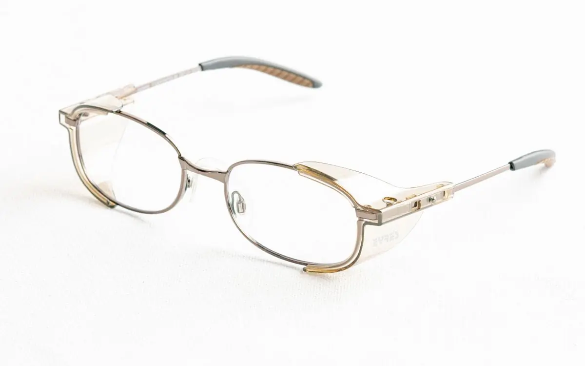 Thin gold metal optical frames resting on a pale surface