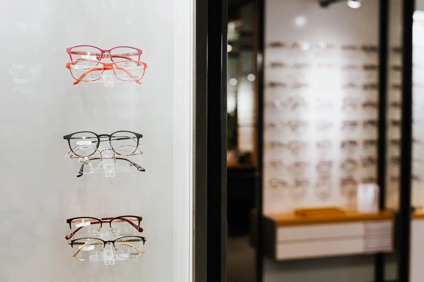 A minimal shop window holding three pairs of frames on white shelves