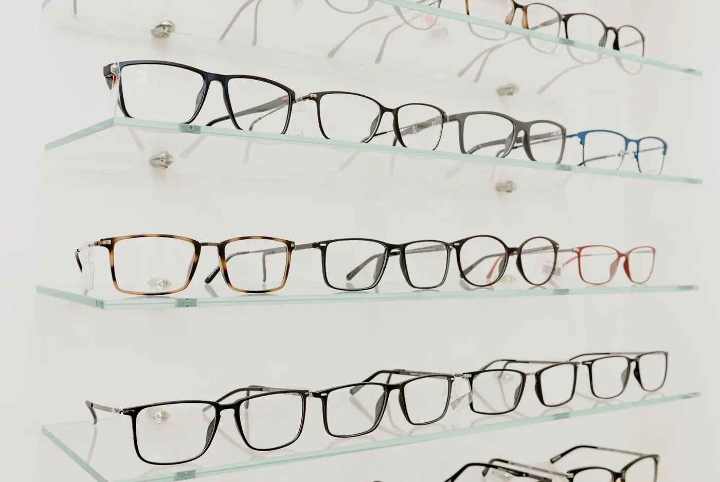 Optical frames arranged along lit glass shelves in a shop