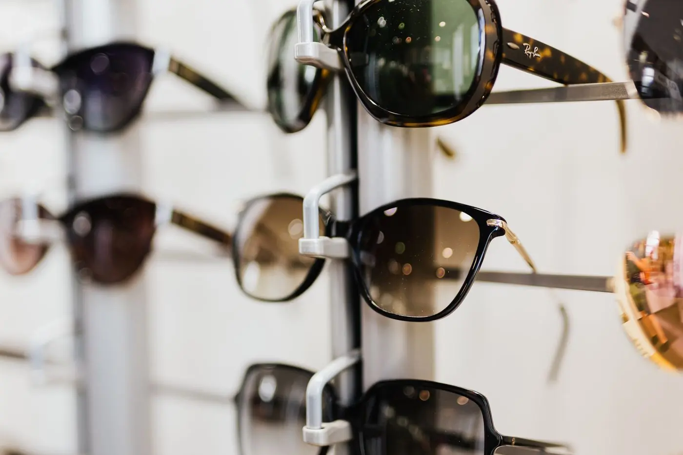 Sunglasses hanging on a display rack in a bright shop