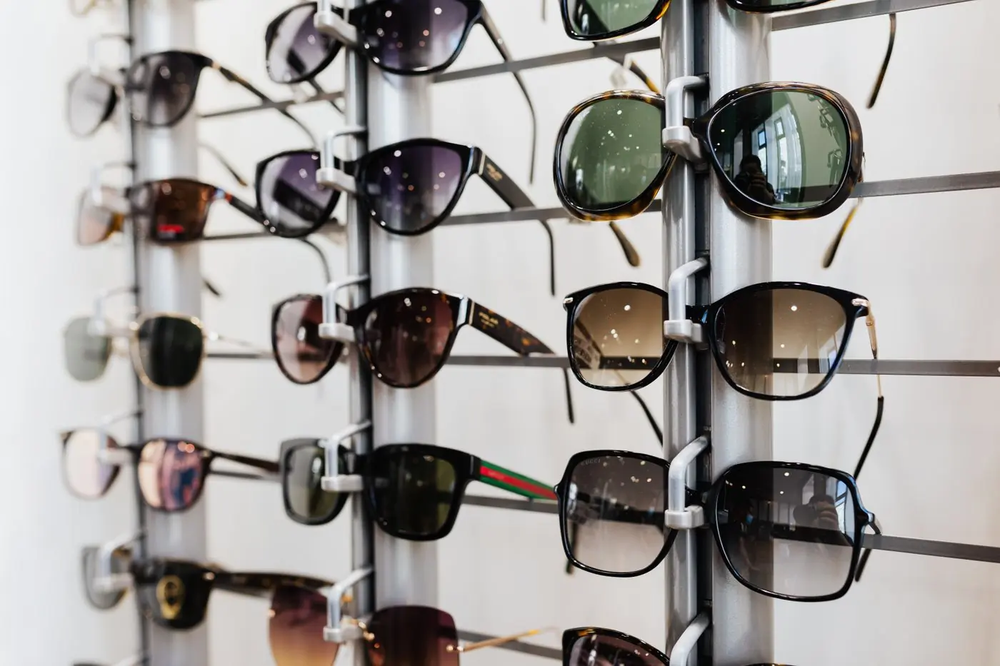 A wall rack of sunglasses in a bright shop