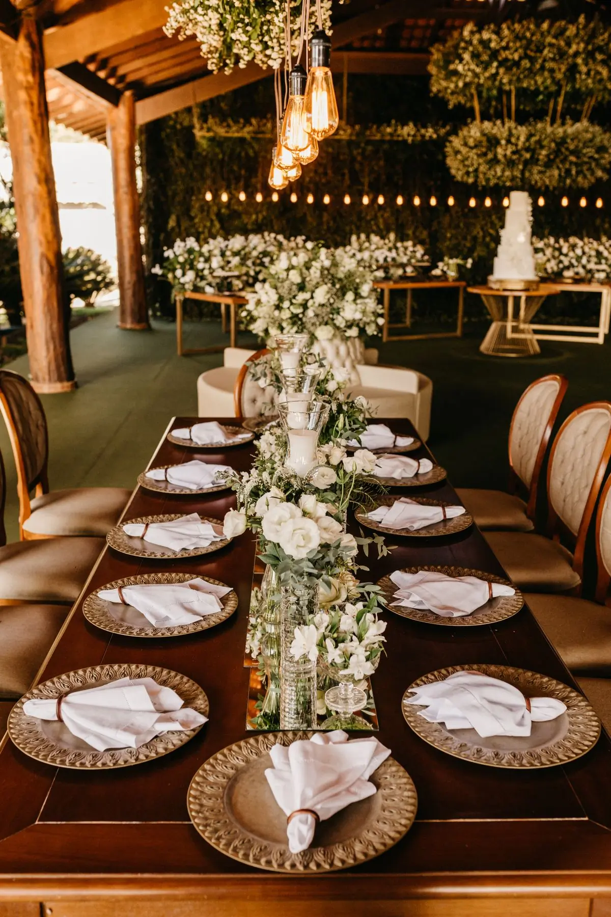 A dark green dining room laid with gold-rimmed plates and white flowers