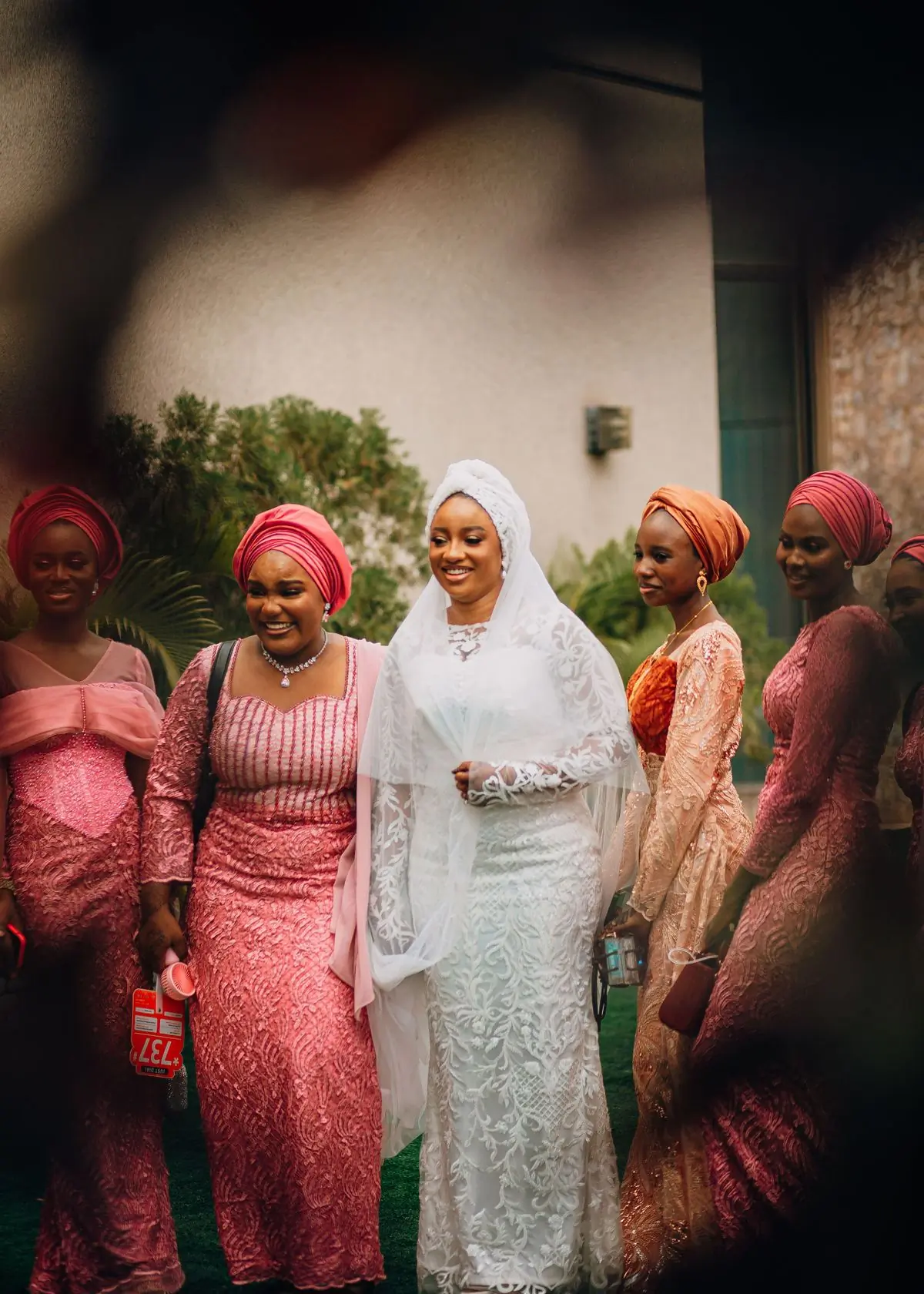 A bride in white walking with her bridesmaids in coral lace