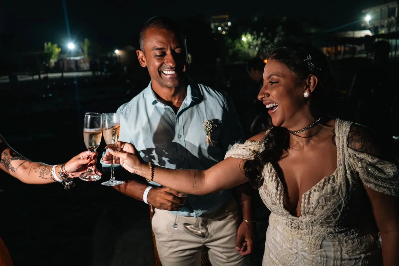 A couple toasting with champagne among their guests at a night wedding