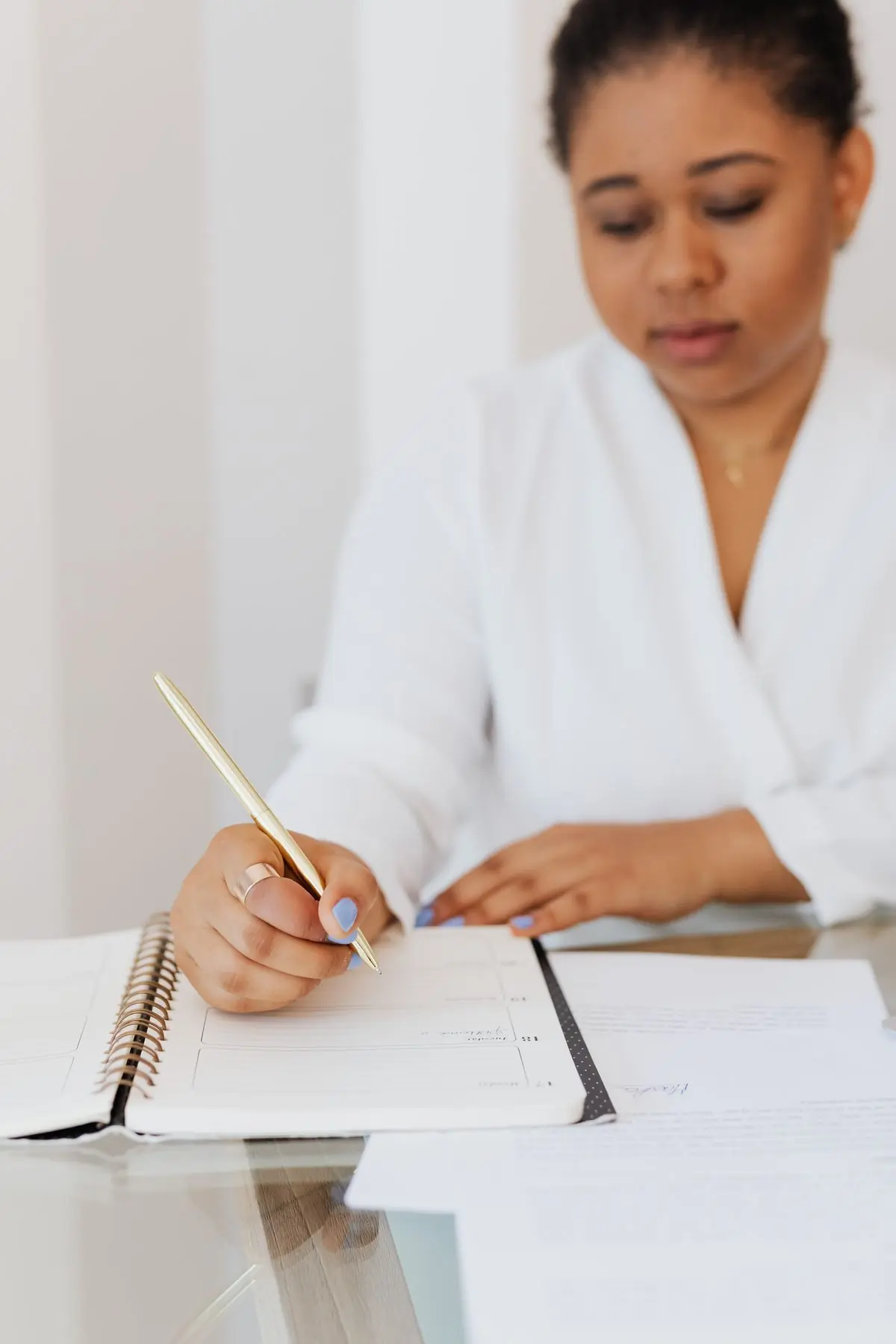 A planner in white at a table, writing a budget by hand