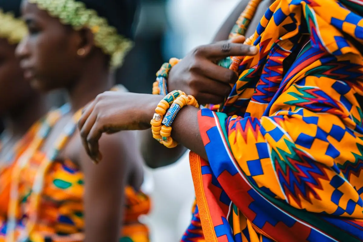 Kente cloth and beaded bracelets on a guest's arm at a customary rite