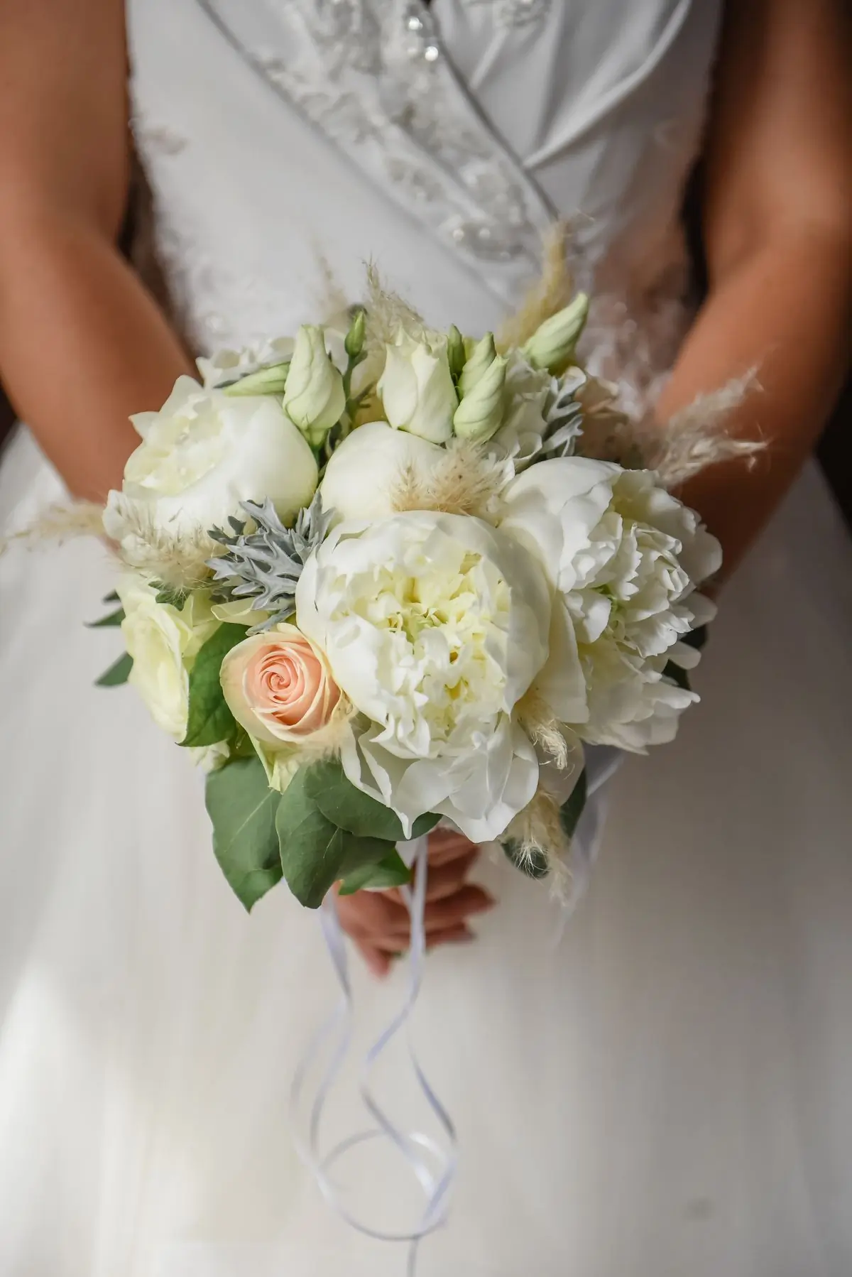 A bridal bouquet of white peonies and pale roses