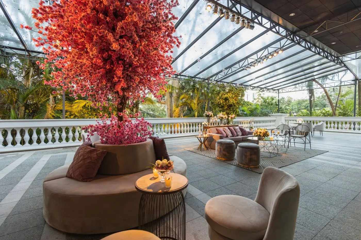 A covered terrace with a blossoming tree, lounge seating and a long balustrade