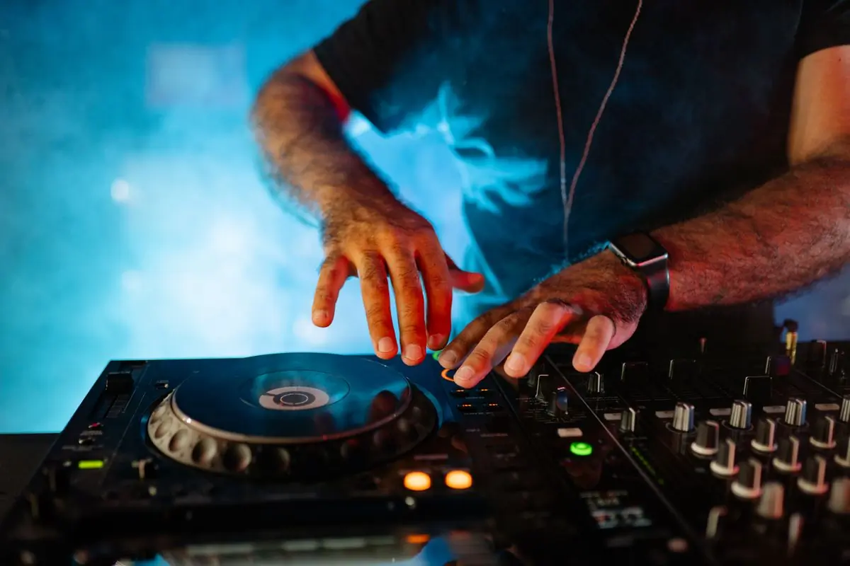 A DJ mixing at a lit booth late at night