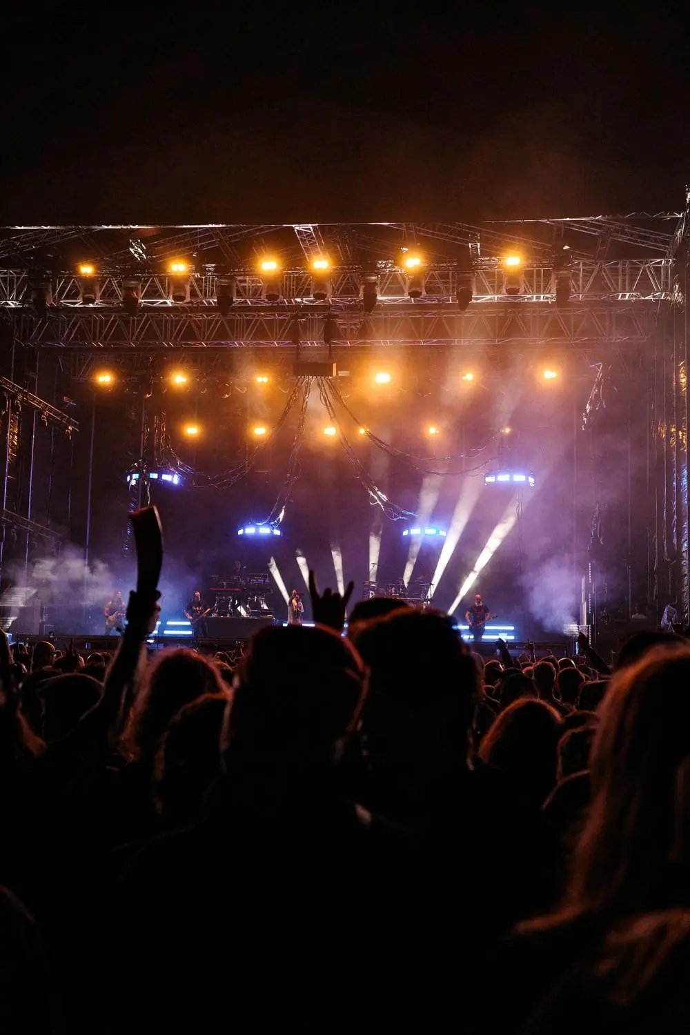 A festival crowd in front of a lit stage at night