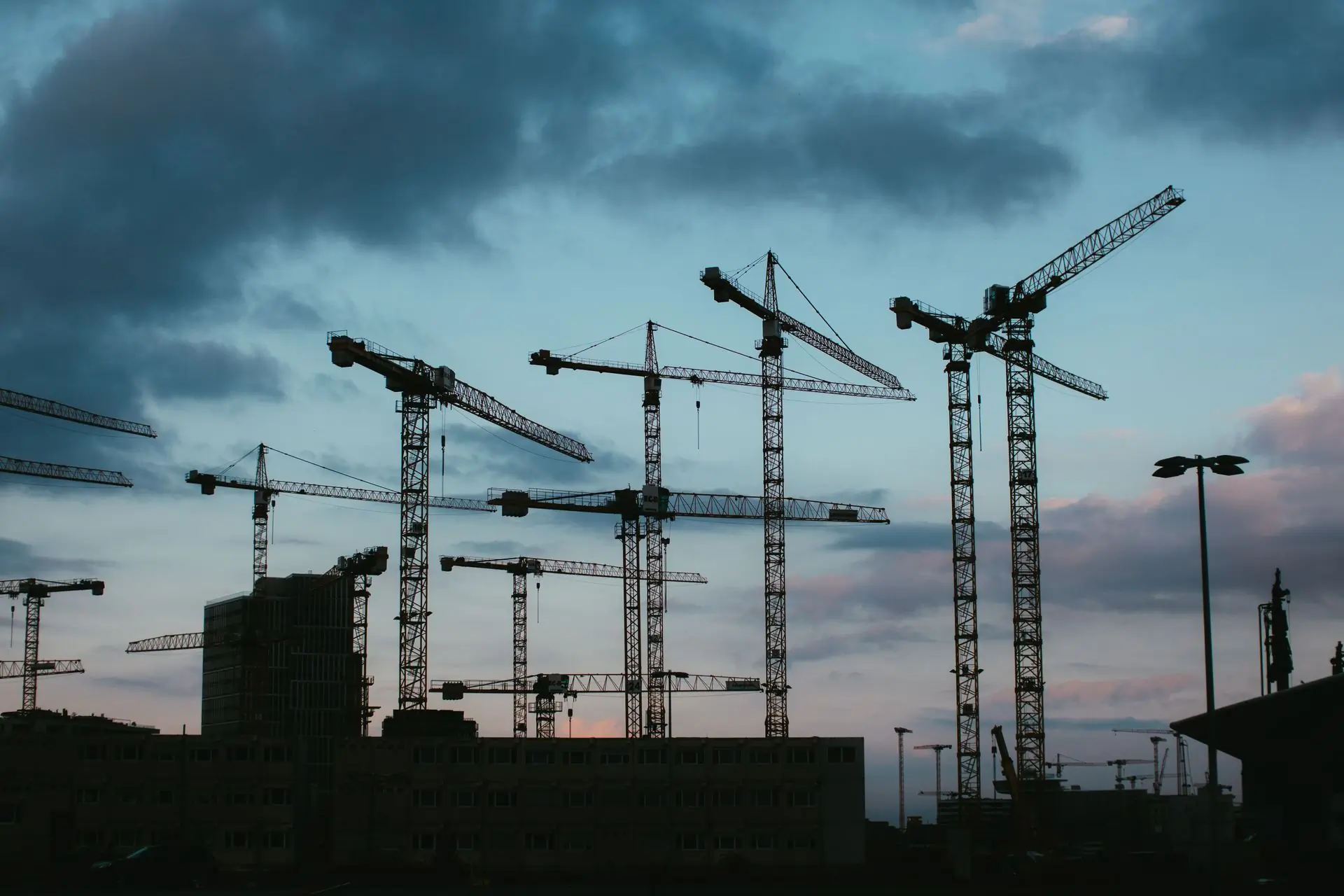 Tower cranes standing over a city site at dusk