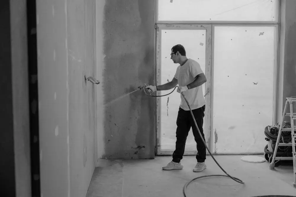 A tradesman spraying a wall during an interior strip-out