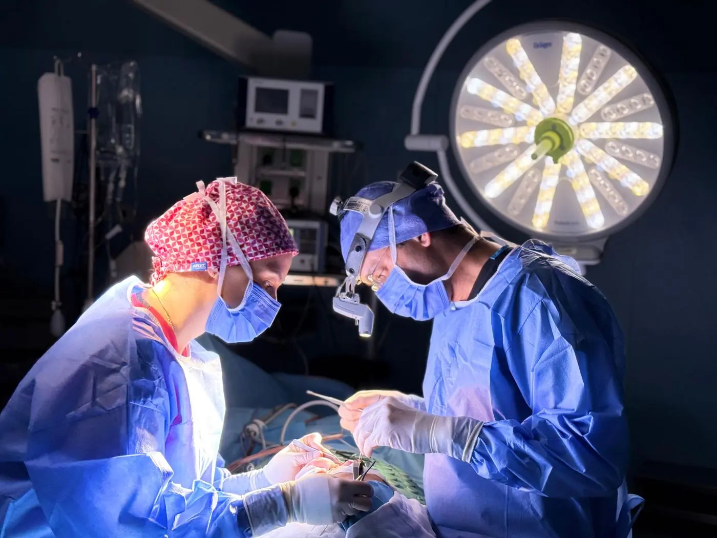 Two surgeons operating under the lights in the centre's theatre
