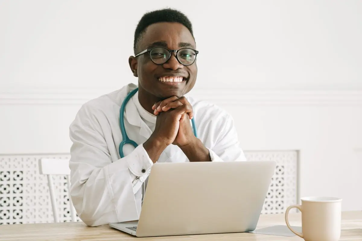 A doctor at the centre smiling at his desk