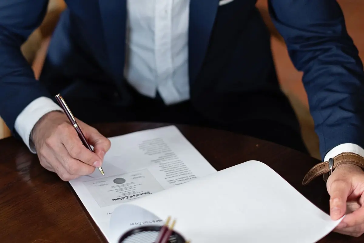 A client signing settlement papers across a desk