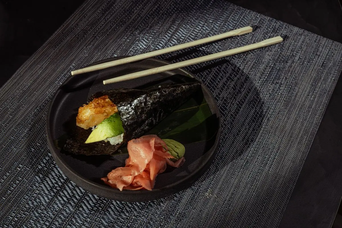 A hand roll resting on a dark plate