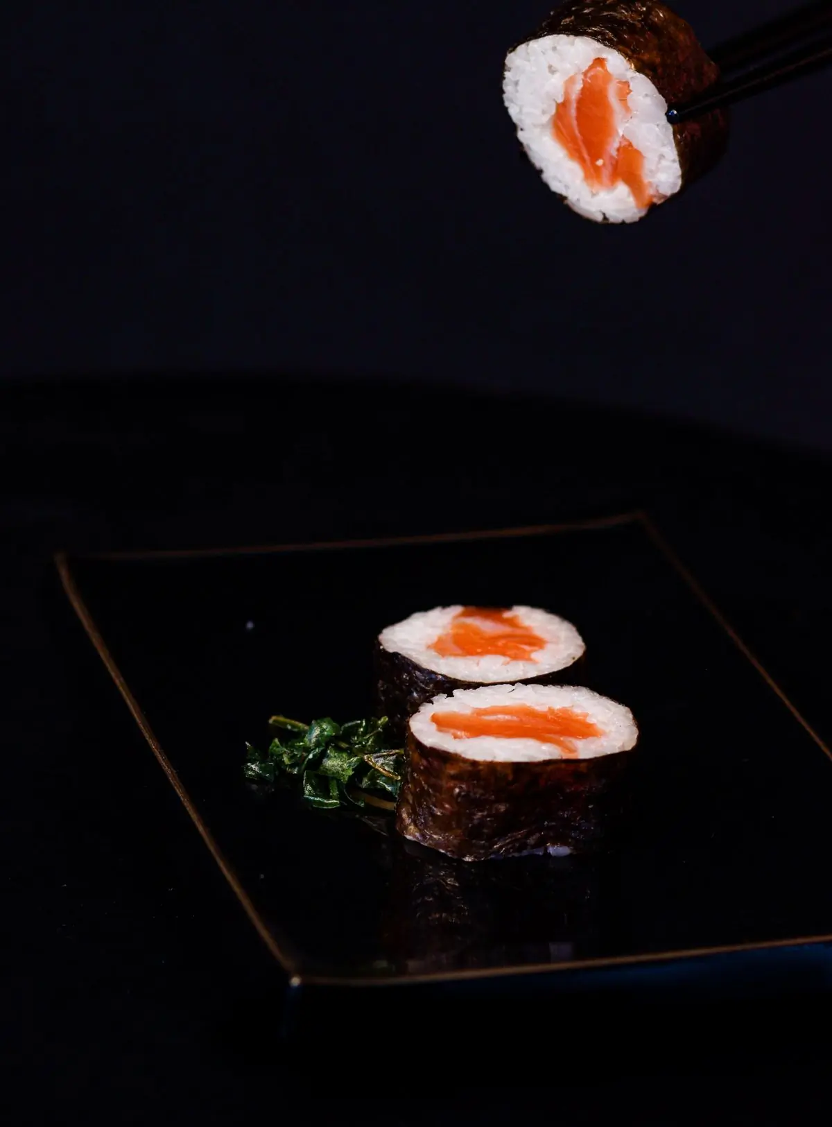 A single maki roll on a black plate