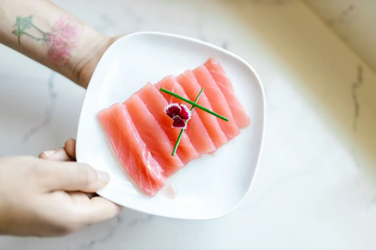 A plate of salmon sashimi held out in both hands