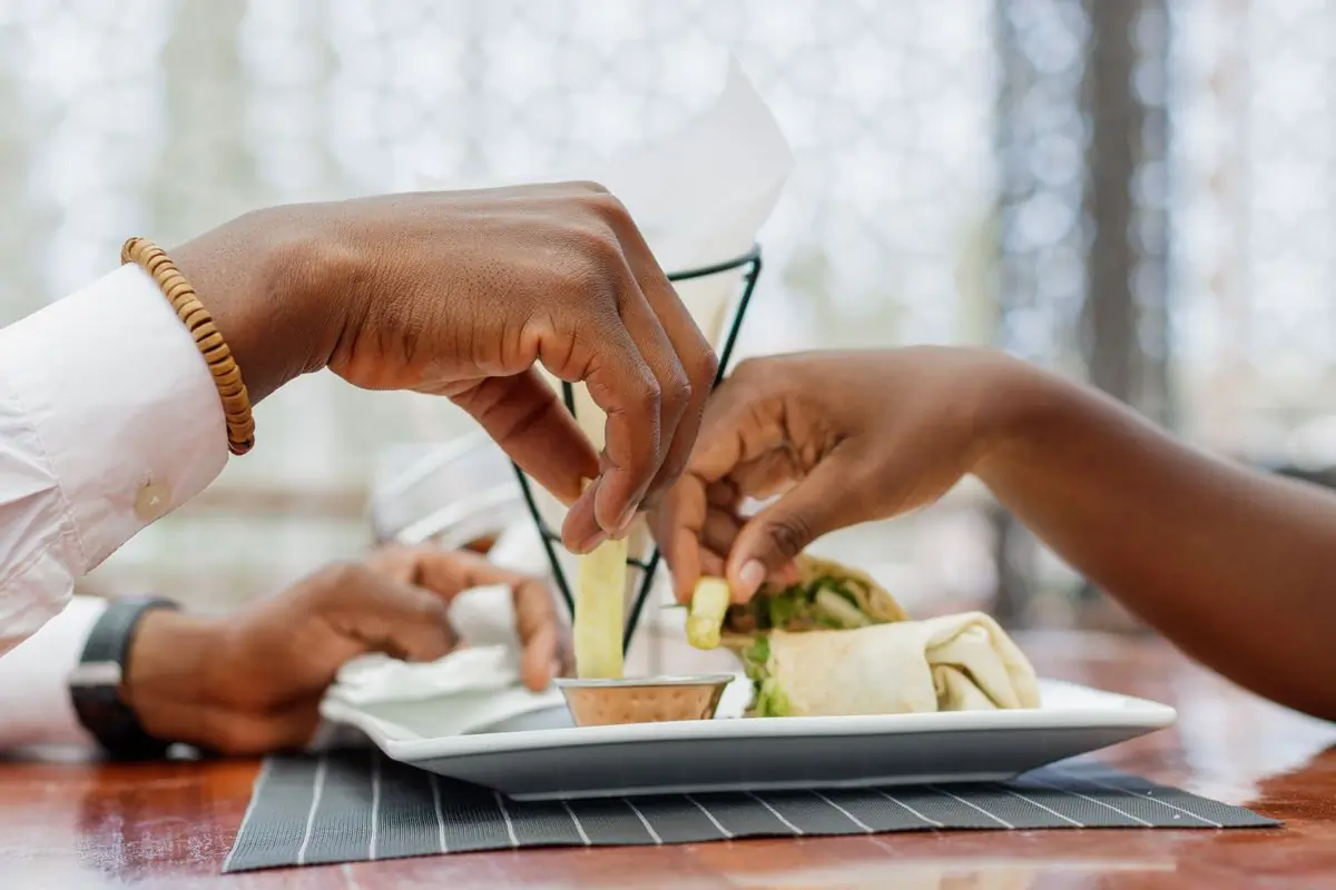 Two guests reaching across a plate at the table