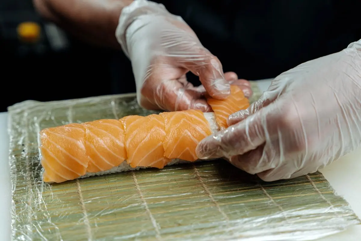A cook laying salmon along a rolling mat