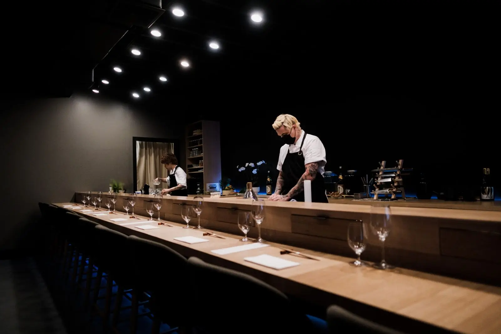 The hinoki counter with a chef working under a low light