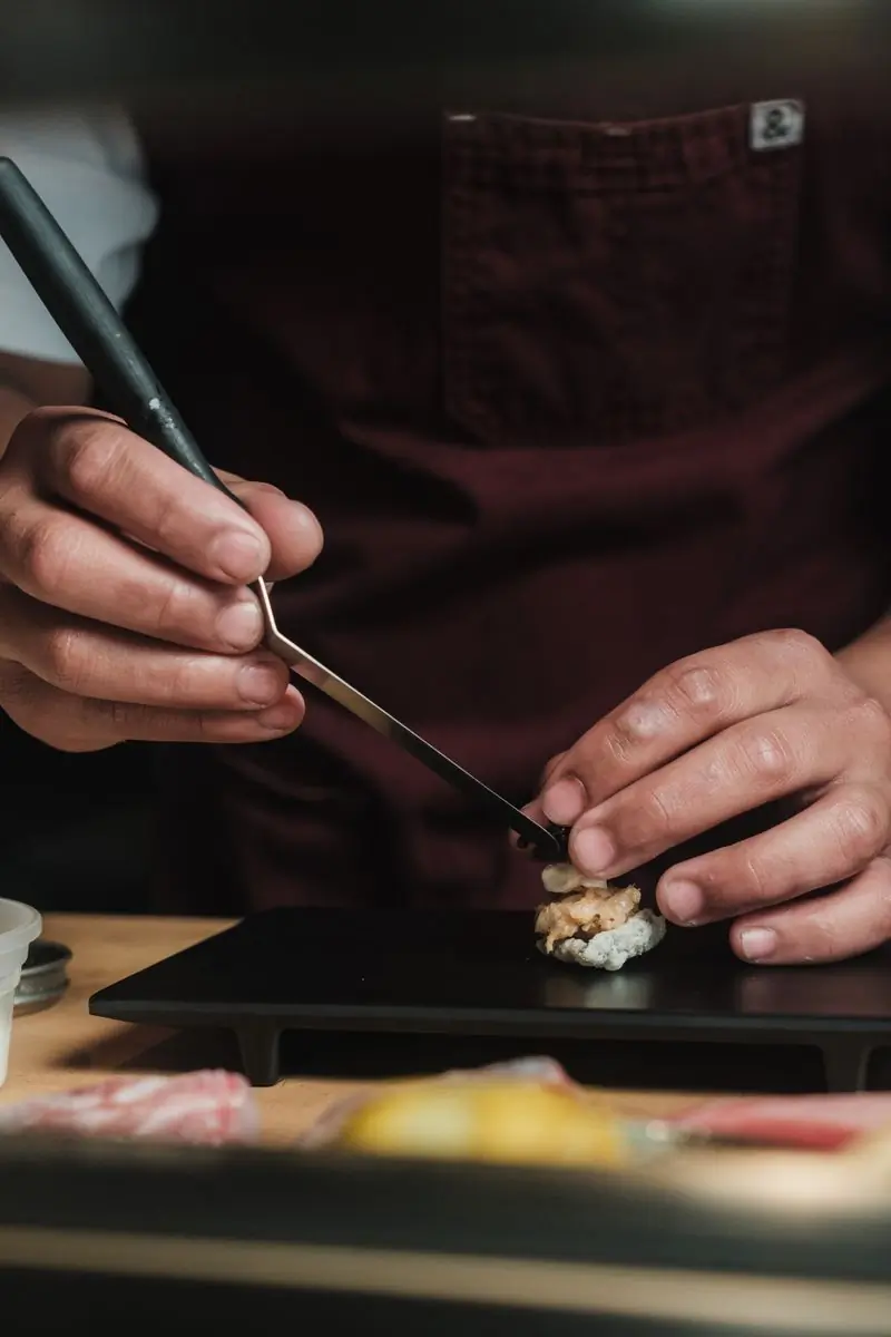 Efua Danquah finishing a piece of nigiri with tweezers