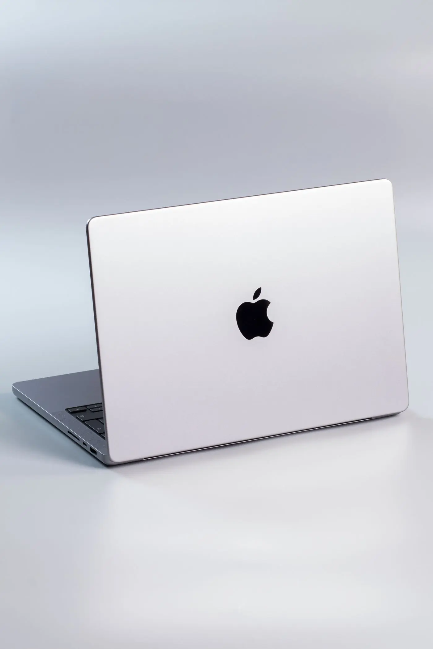 A closed silver laptop photographed on a studio ground