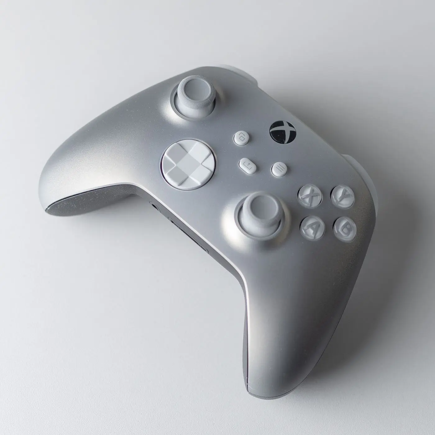 A grey and white game controller on a white surface