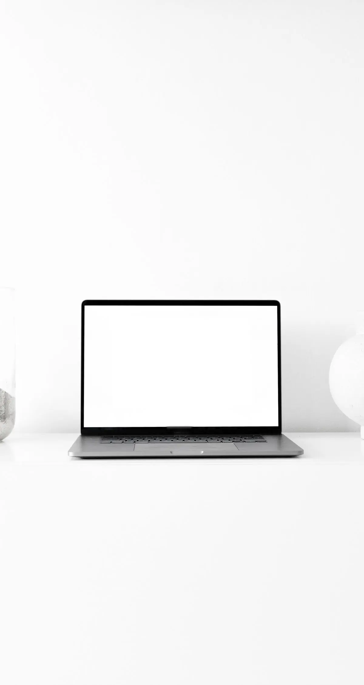 An open laptop with a blank screen on a pale desk