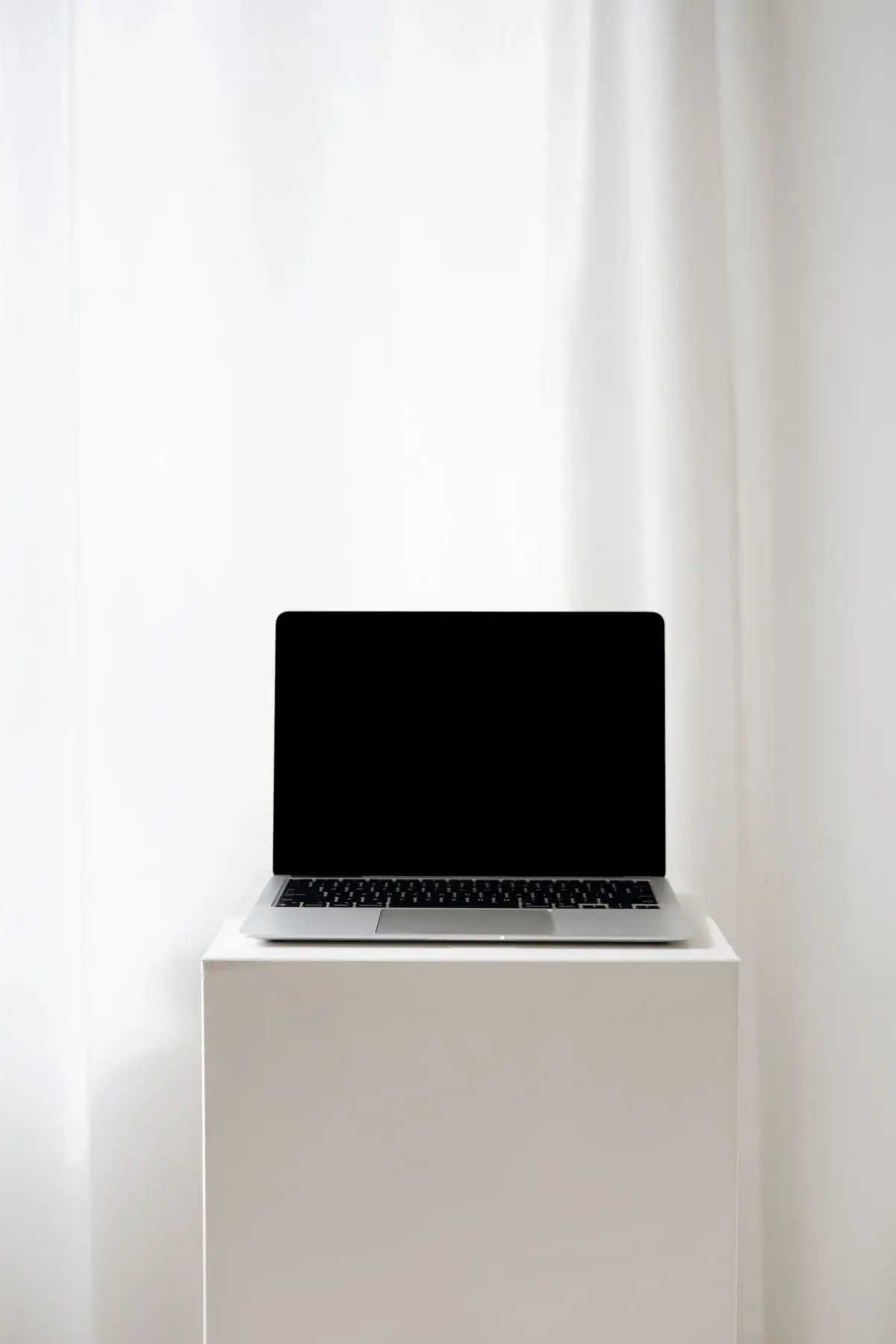 A laptop with a blank screen on a white pedestal