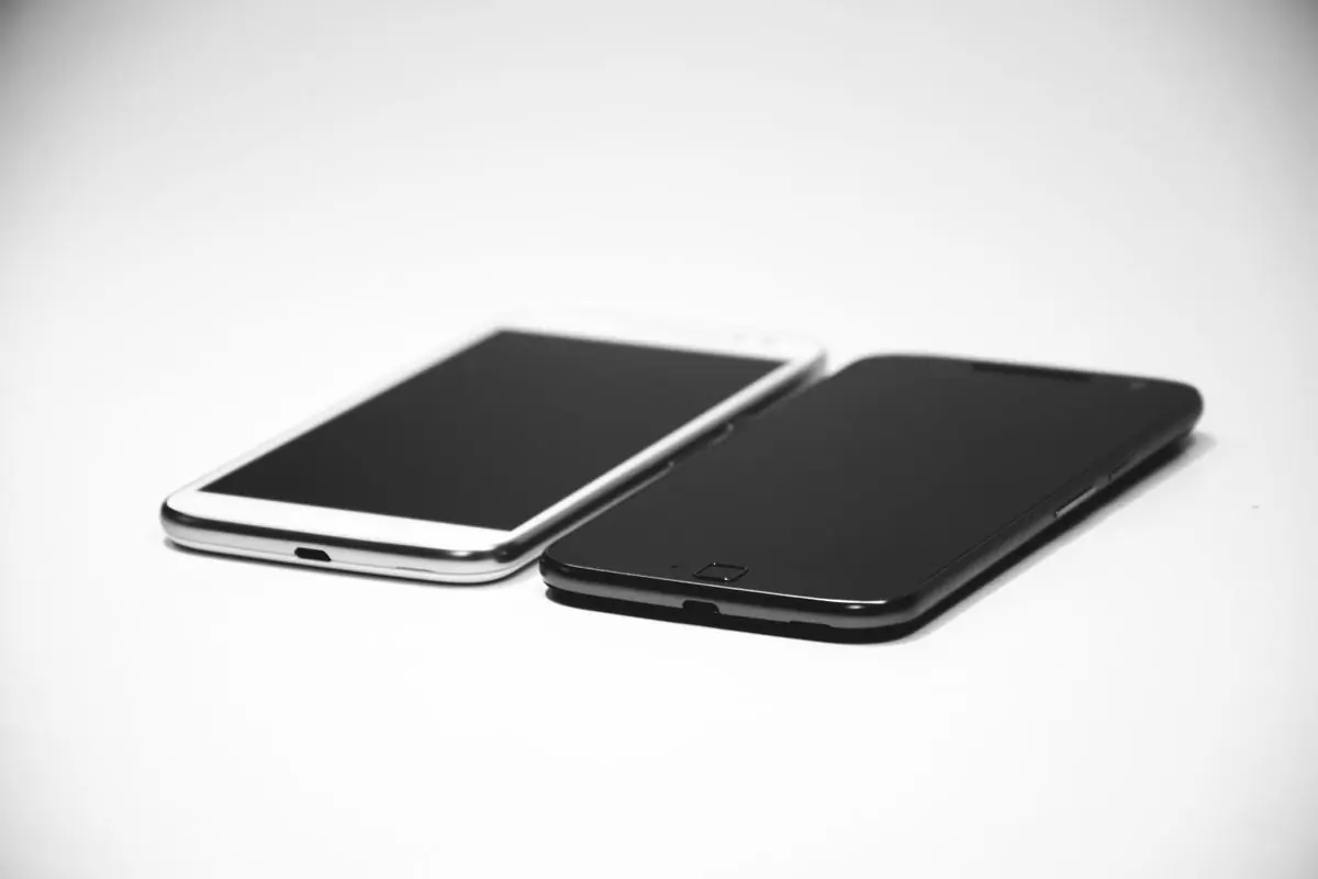 Two smartphones lying side by side on a white surface