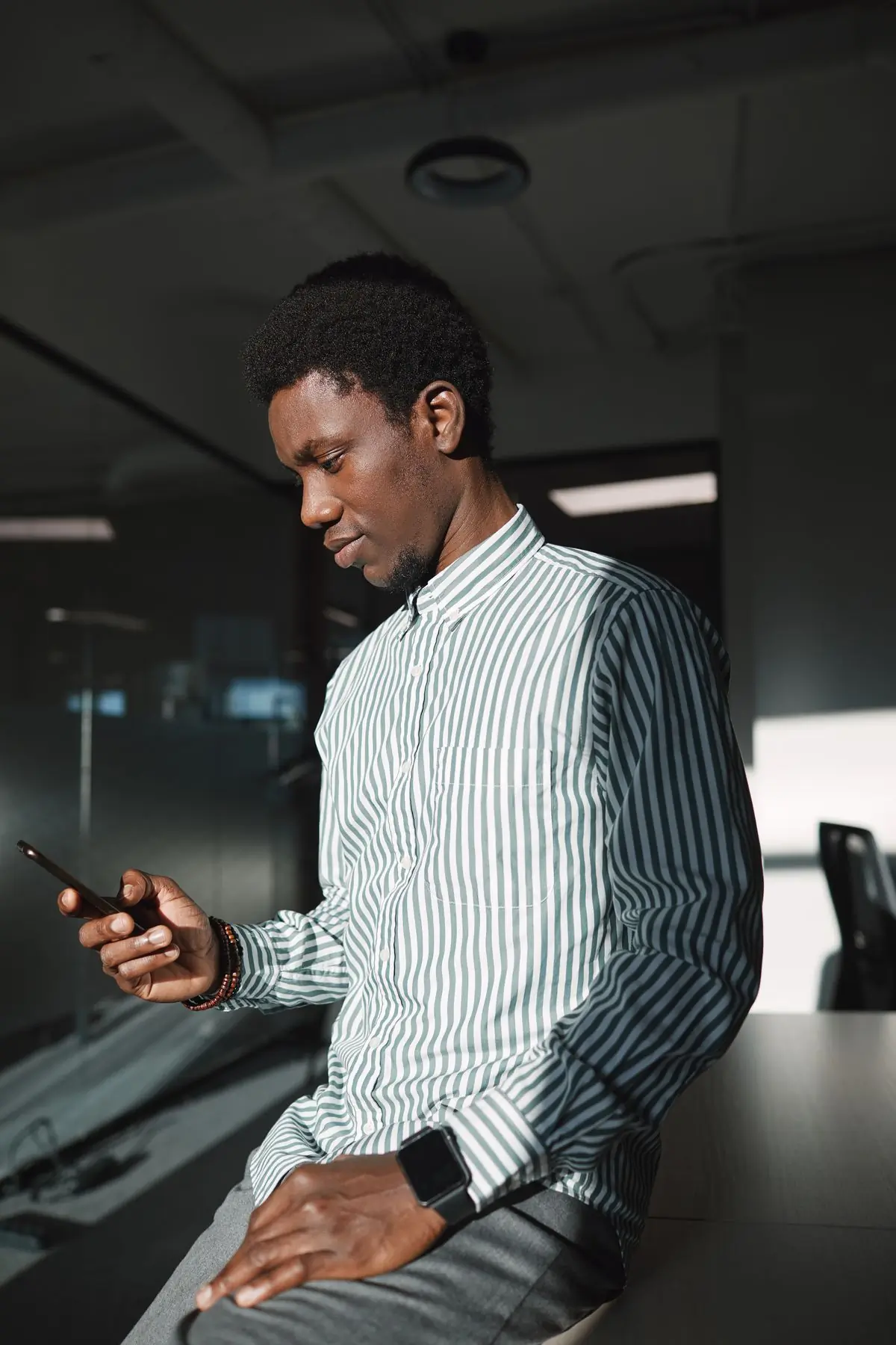 A man in a striped shirt checking a phone on the shop floor