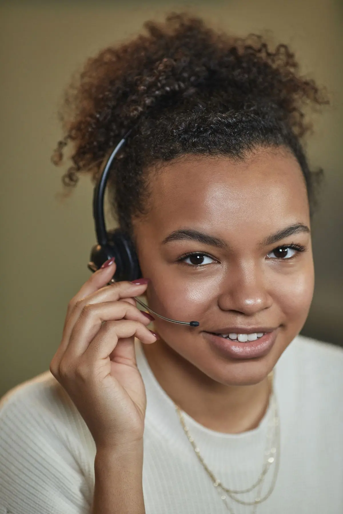 A support agent wearing a headset, smiling at a desk