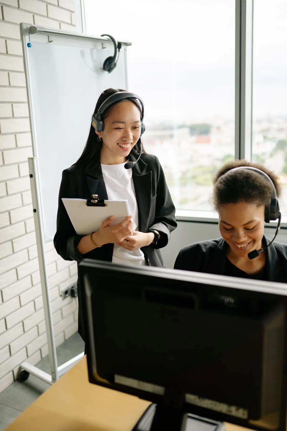 Two colleagues in headsets going through a clipboard together